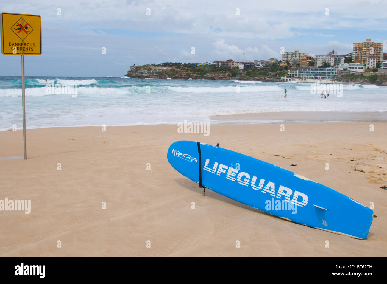 Bondi Beach, Sydney Australien Aussie Surfen Surfer blaue Meer Waveboard zu Fuß aus großen Neoprenanzug sonnigen Tag blauen Himmel Sonnenbaden sand Stockfoto