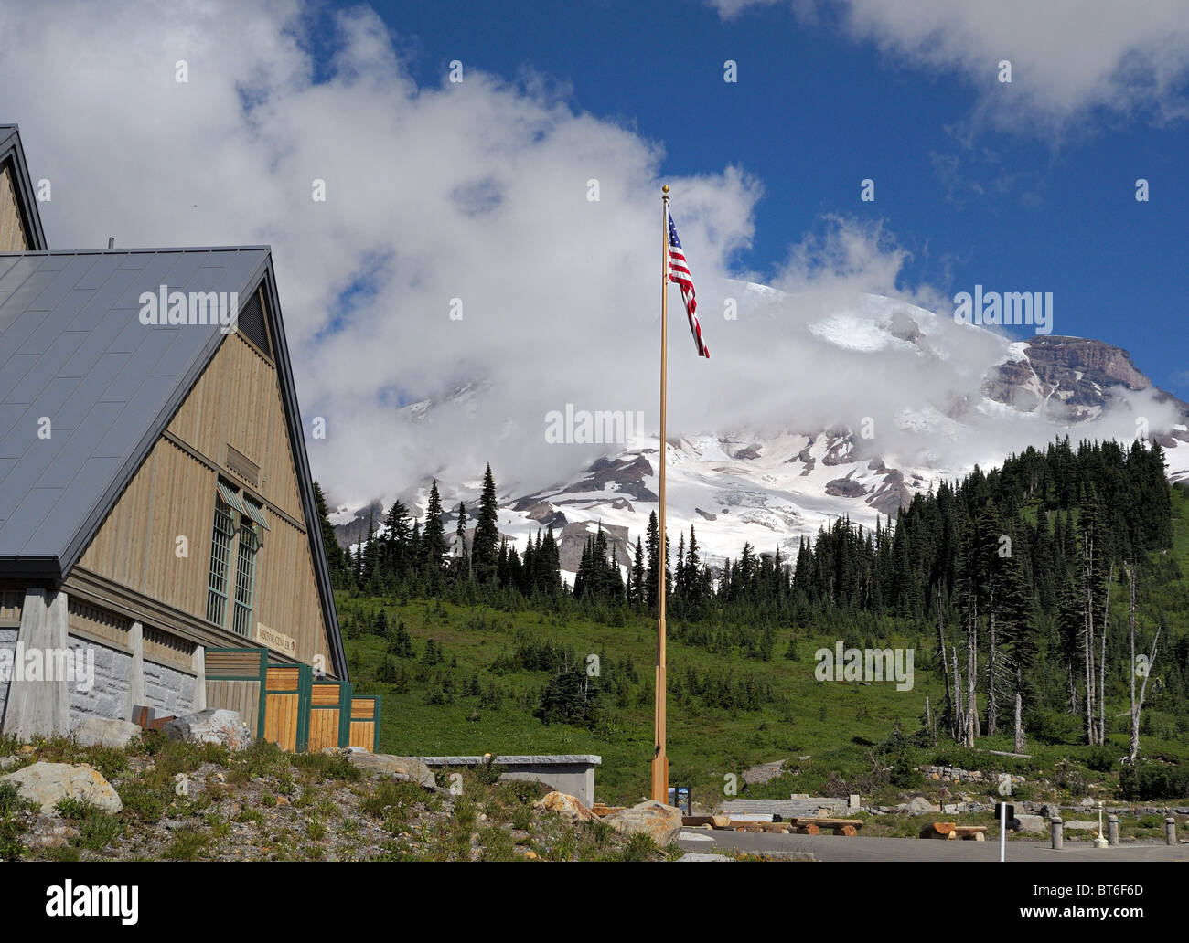 Das Henry M. Jackson Visitor Center am Mt. Rainier National Park, mit einer rustikalen Holzfassade und einer amerikanischen Flagge mit dem schneebedeckten Gipfelteil Stockfoto