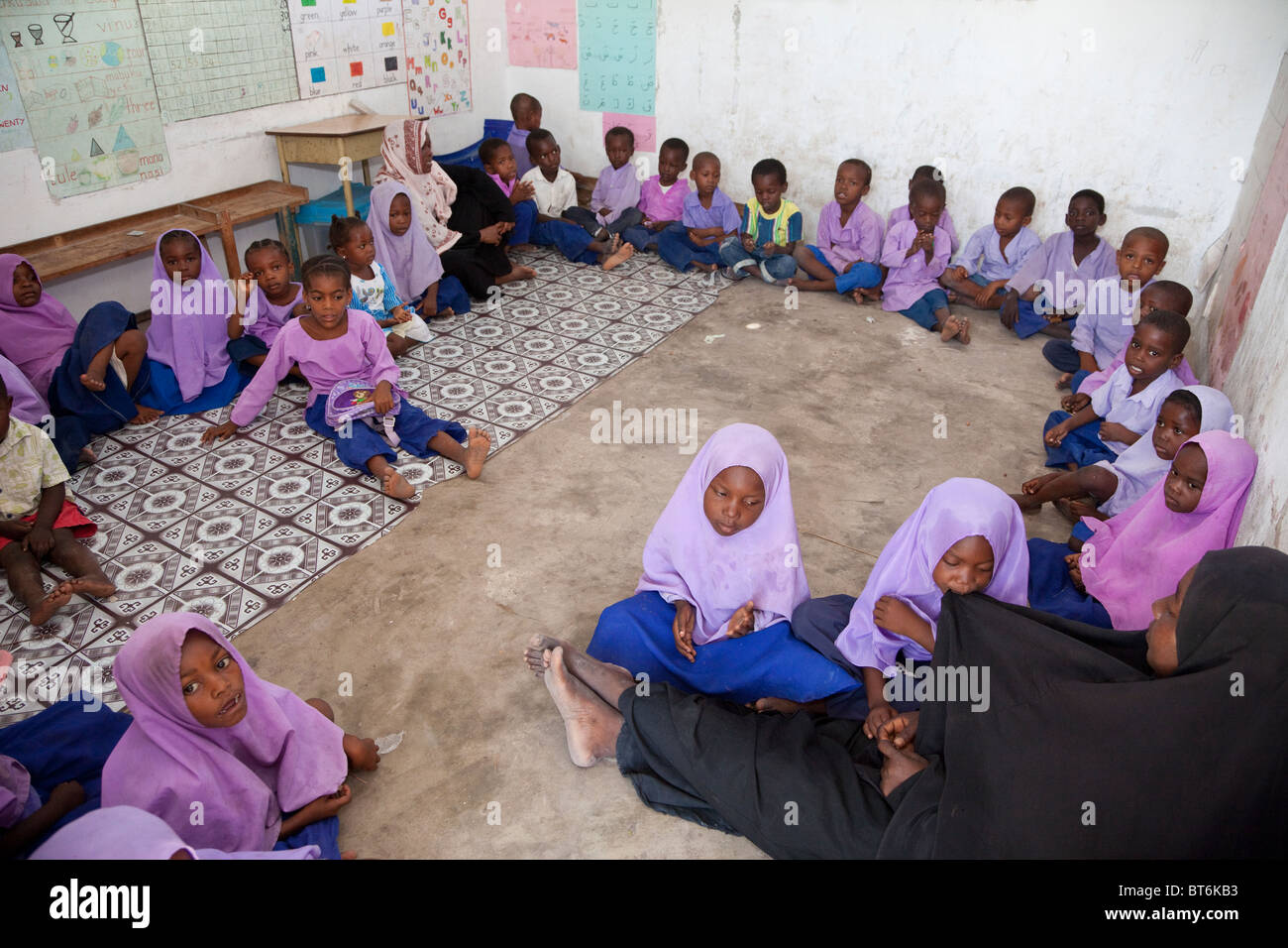 Jambiani, Sansibar, Tansania. Grundschule Unterricht, Schülerinnen und Schüler. Die Schüler sitzen auf dem Boden und die Schule hat keine Möbel. Stockfoto