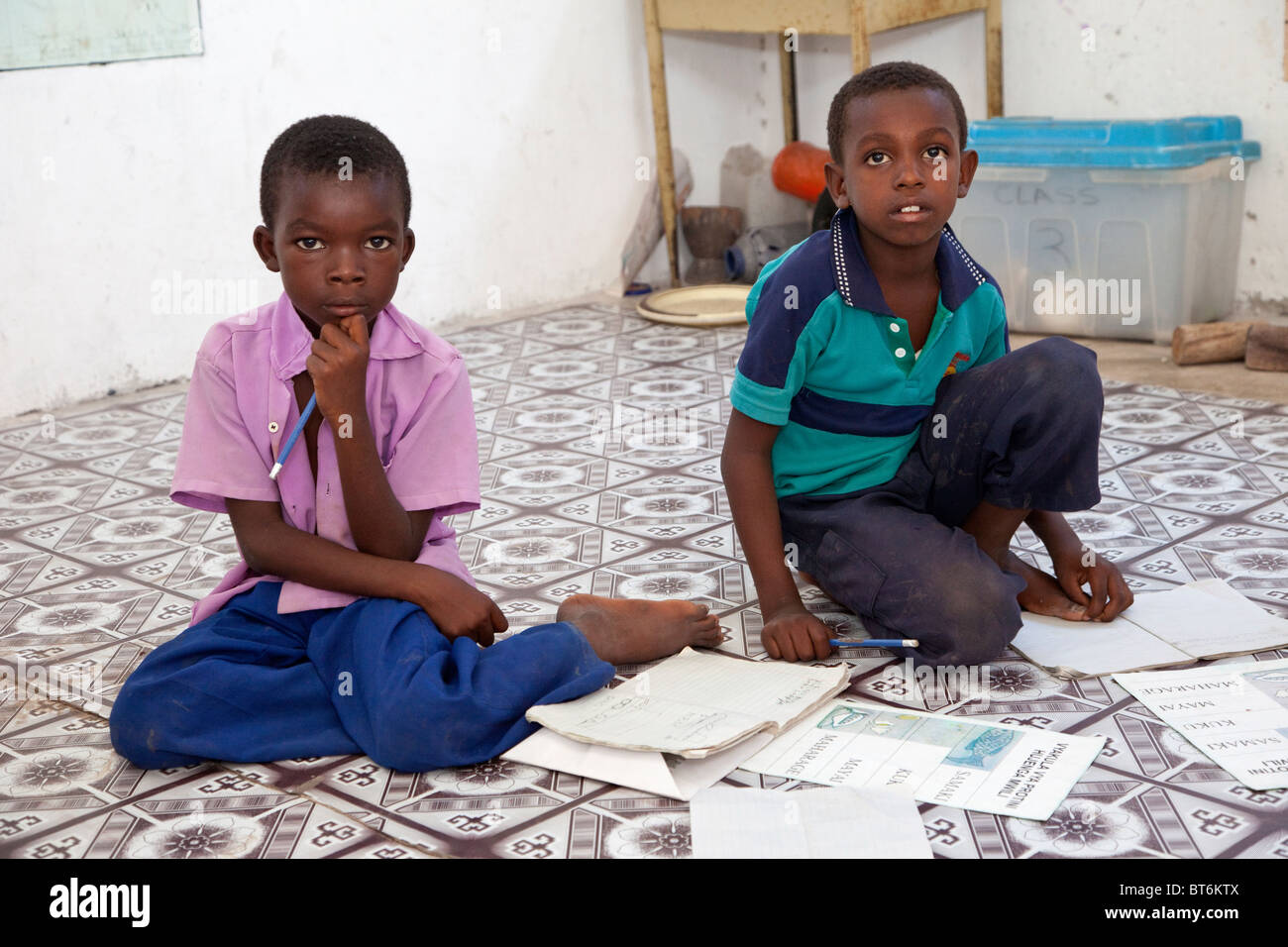 Jambiani, Sansibar, Tansania. Primary School Boys und ihren Arbeitsmappen. Studenten sitzen auf dem Boden; die Schule hat keine Möbel. Stockfoto