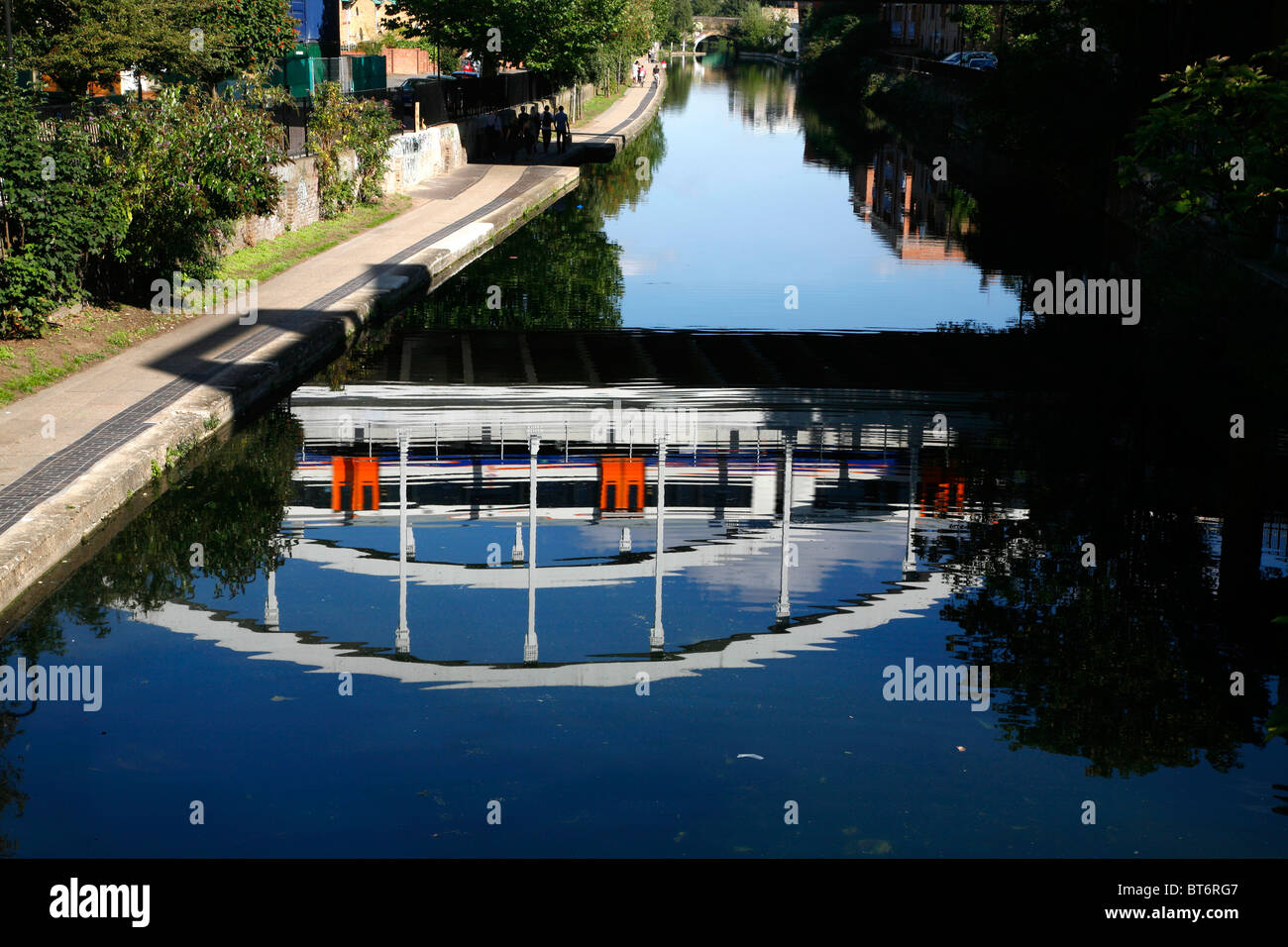 East London Line-Zug (Overground) spiegelt sich im Wasser des Regent es Canal in Haggerston, London, UK Stockfoto