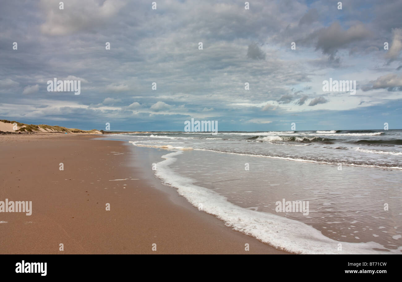 Sonnenstrand mit blauer Himmel, Wolken und brechenden Wellen an der Druridge Bucht, Northumberland Küste, North East England. Stockfoto