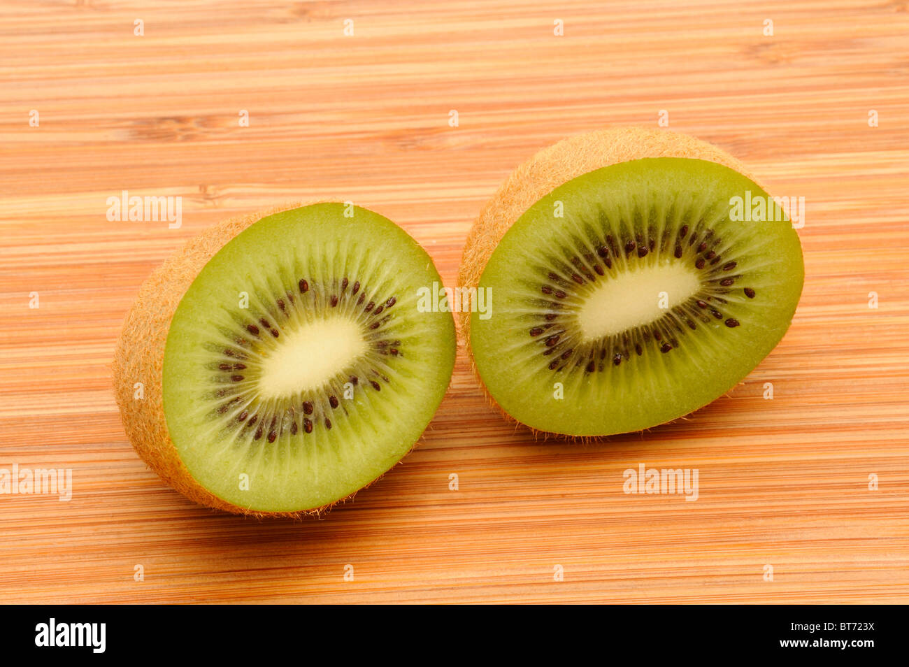Kiwi (Schnitt Deliciosa), schneiden in der Mitte auf einem Holzbrett Stockfoto
