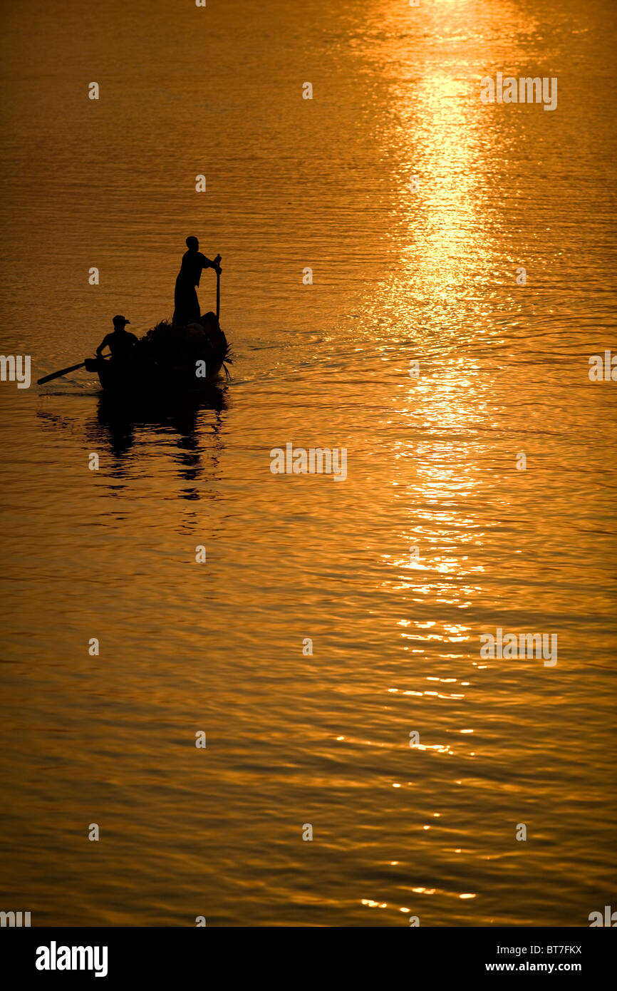 Bootsführer Rudern auf einem Fluss von goldenen Sonnenuntergang beleuchtet Stockfoto
