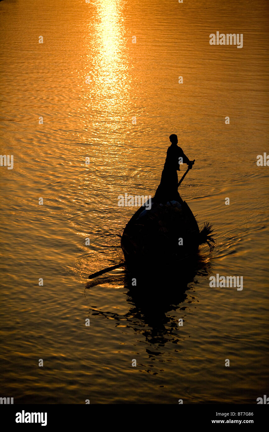Bootsführer Rudern auf einem Fluss von goldenen Sonnenuntergang beleuchtet Stockfoto
