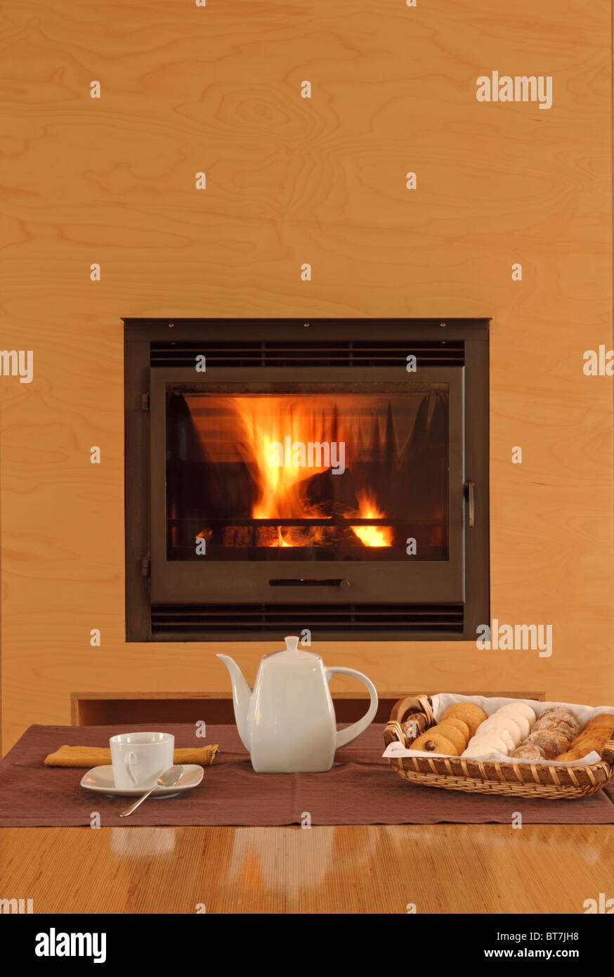 Weiße Keramik Teekanne und Tasse Cookies auf einem Tisch vor einem Kamin Stockfoto