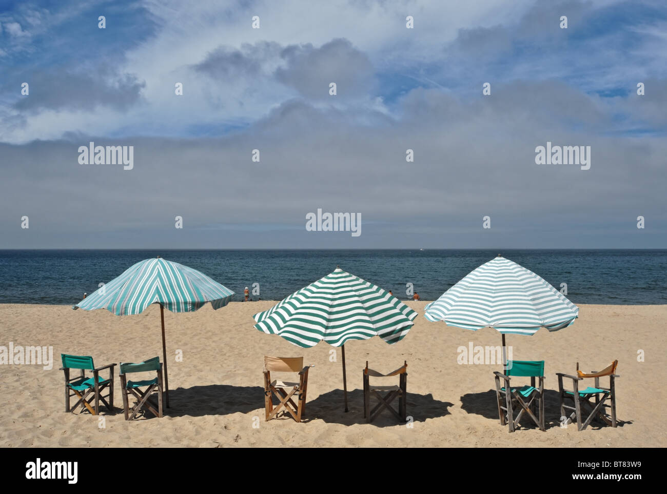 Drei Sonnenschirme mit Stühlen auf dem Sand am Strand von Figueira da Foz in Portugal Stockfoto