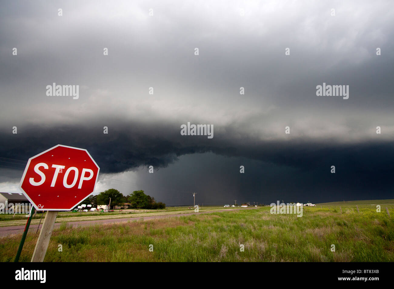 Ein Stopsign kennzeichnet eine Kreuzung mit einem bald zu tornadischen supercellular Gewitter im Hintergrund in der Nähe von Scottsbluff, NE Stockfoto