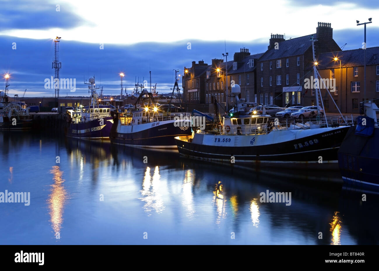 Die Fischerei Dorf von Peterhead im Nordosten von Schottland, UK, gesehen beleuchtet am Abend mit Fischerboote vertäut Stockfoto