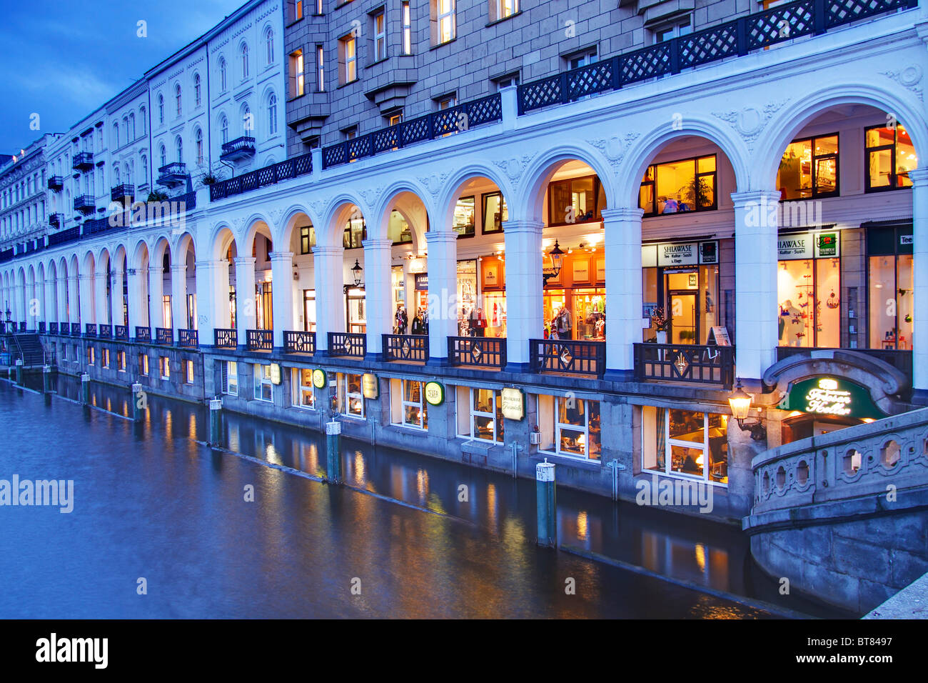 Einkaufspassagen, Alsterarkaden, mit dem Friesenkeller-Restaurant über die Kleine Alster-Kanal im Abendlicht beleuchtet Stockfoto