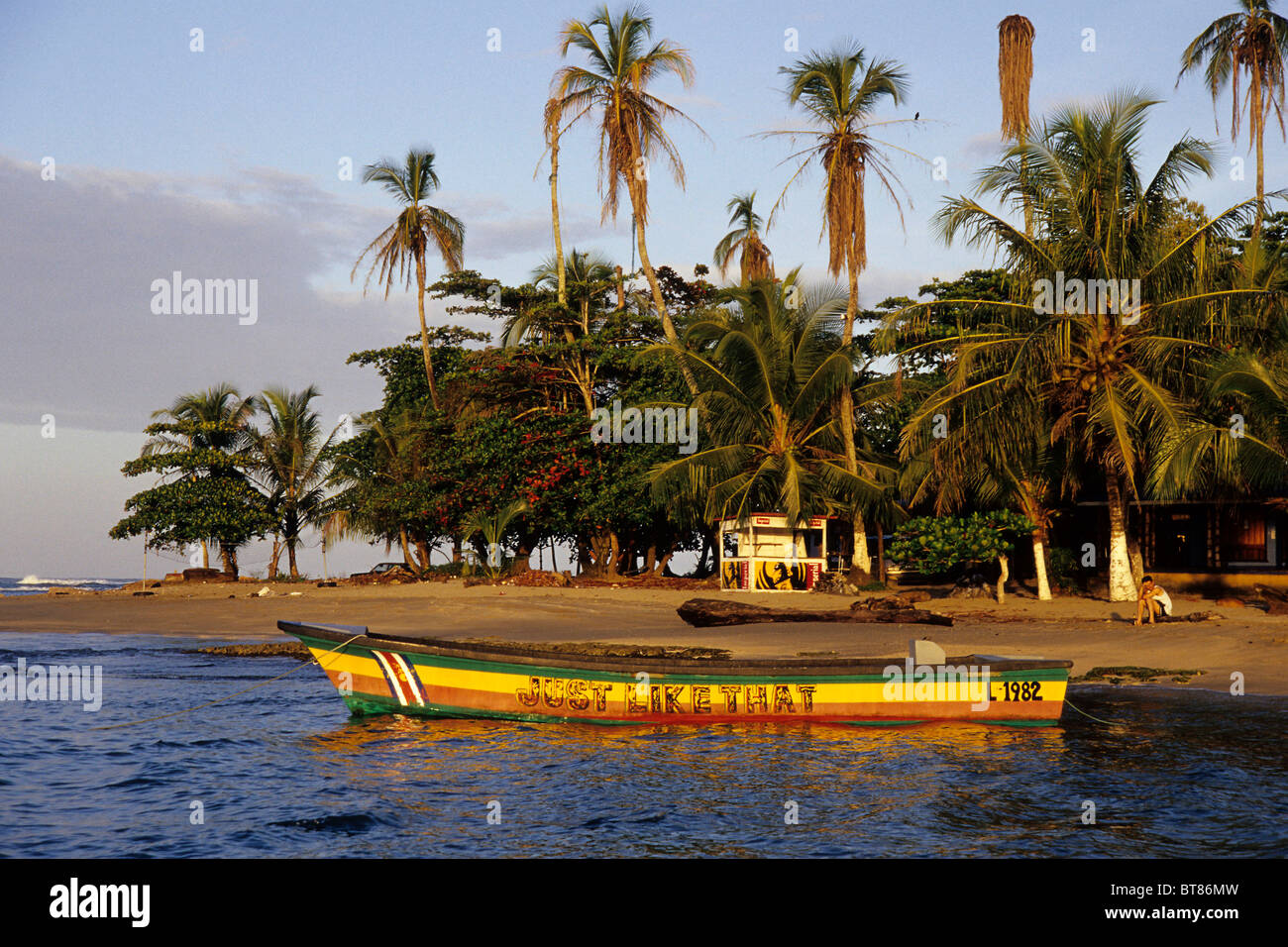 Kleines Boot gemalt in Reggae Farben an einem tropischen Strand mit Palmen, Puerto Viejo de Talamanca an der Karibikküste Stockfoto