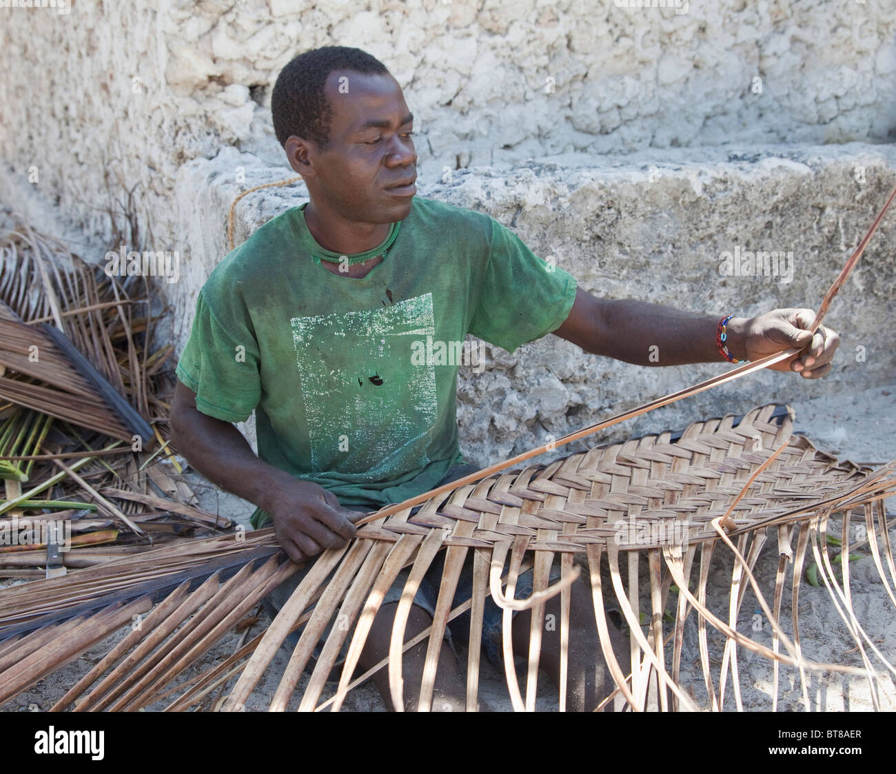 Jambiani, Sansibar, Tansania. Mann eine Matte aus Palmwedeln weben. Stockfoto