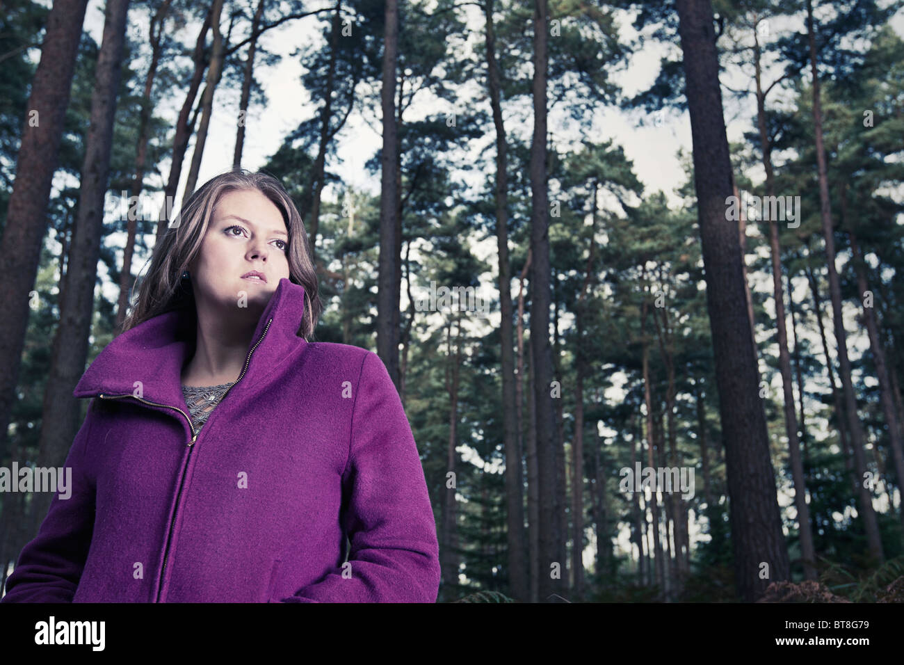 Aufnahme einer Frau in lila Mantel im Wald Stockfoto