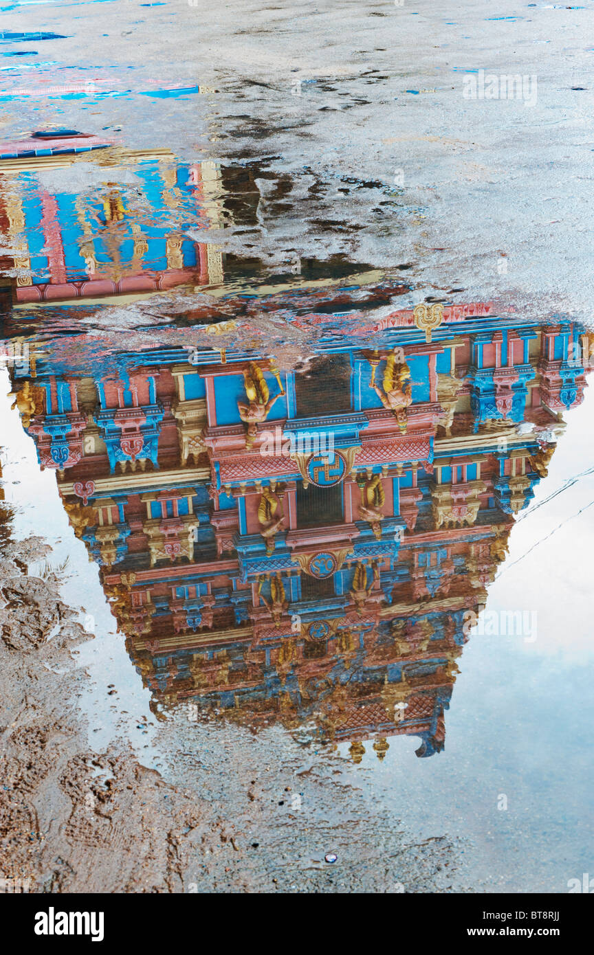 Indische gopuram Temple Gate in einer Pfütze von Regenwasser zu reflektieren. Puttaparthi, Andhra Pradesh, Indien Stockfoto