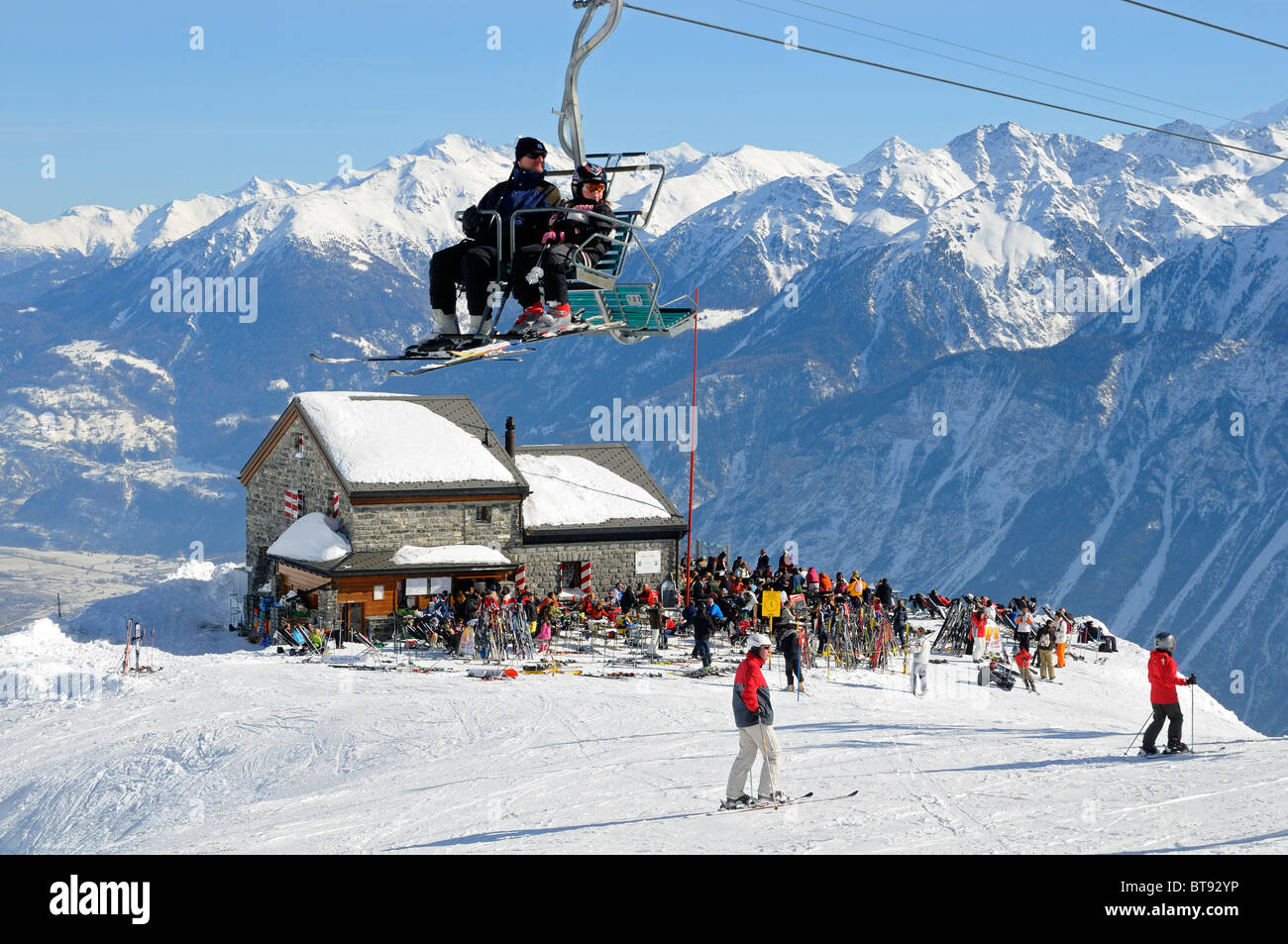 Skifahrer, die auf einem Stuhl sitzend heben schwebt über der Hütte Les Violettes in den Walliser Alpen, Crans-Montana, Wallis, Schweiz Stockfoto