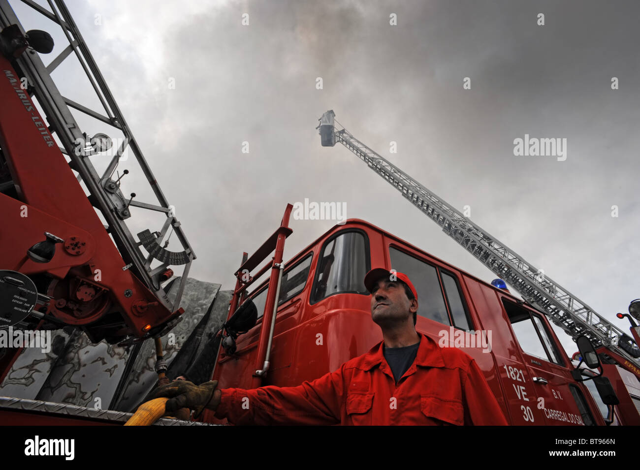 Feuerwehrmann nach oben neben einem Feuerwehrauto mit einer Ausziehleiter Stockfoto