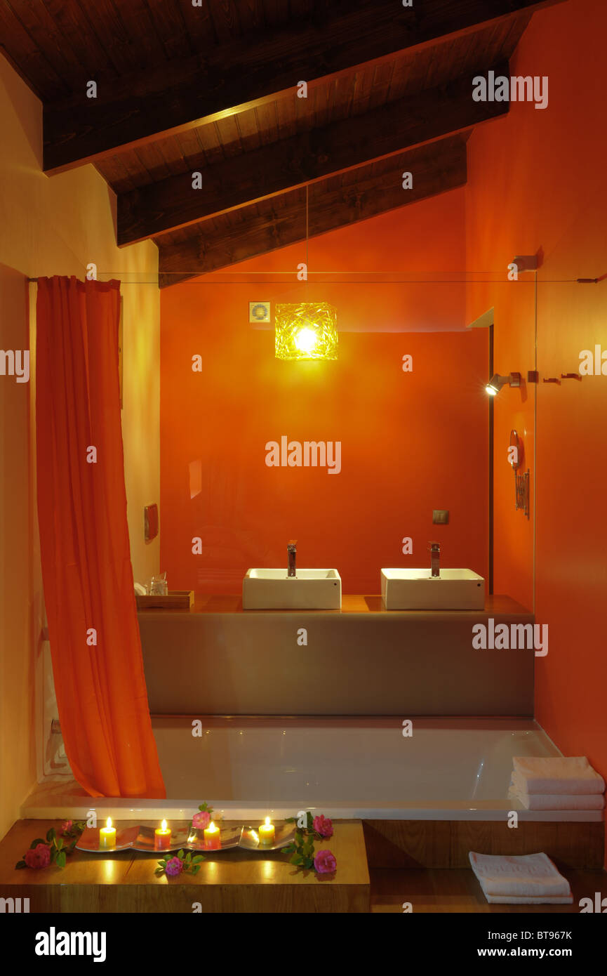 Orange Badezimmer,, Badewanne mit orange Vorhang, zwei Waschbecken und Kerzen Stockfoto