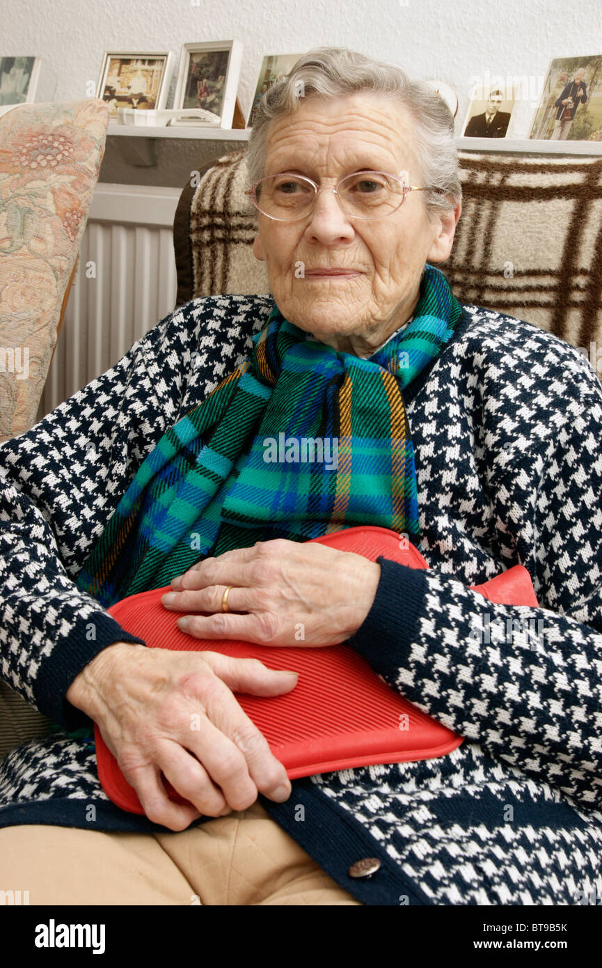 ältere Frau Warmhalten im Winter tragen eine dicke Strickjacke mit einer Wärmflasche speichern immer Hypothermie Stockfoto