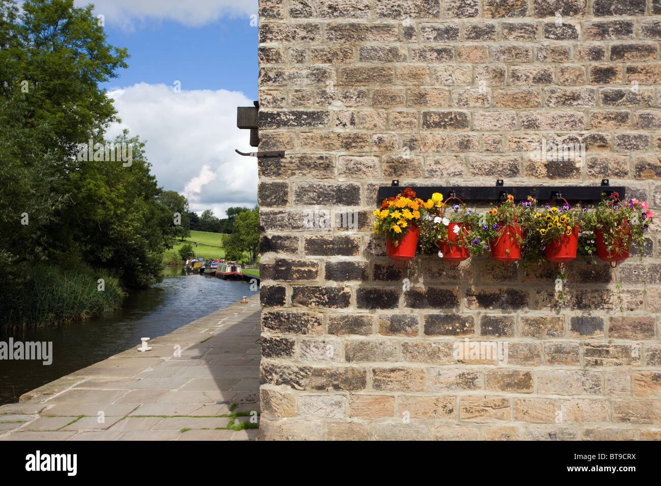 Blumen im Feuer Eimer bei Cafe Cargo am Leeds-Liverpool-Kanal in Foulridge, Lancashire Stockfoto