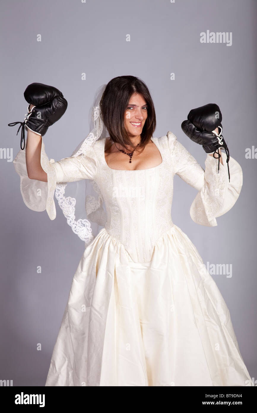 Verrückte schöne Braut mit Boxhandschuhen (grauer Hintergrund) Stockfoto