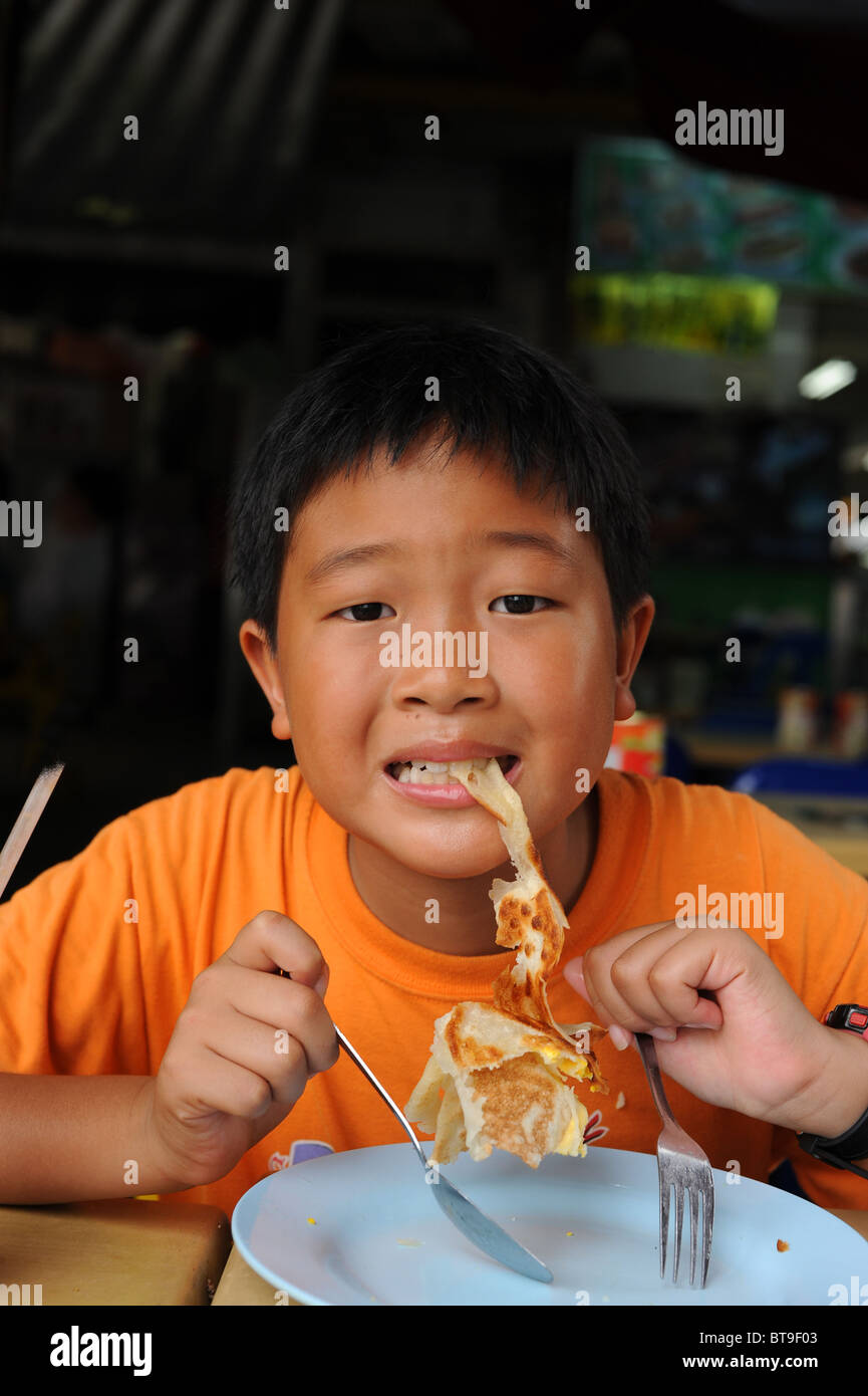 Boy neun Jahre genießen ein Roti Prata in lokalen Singapore Food-Court Stockfoto