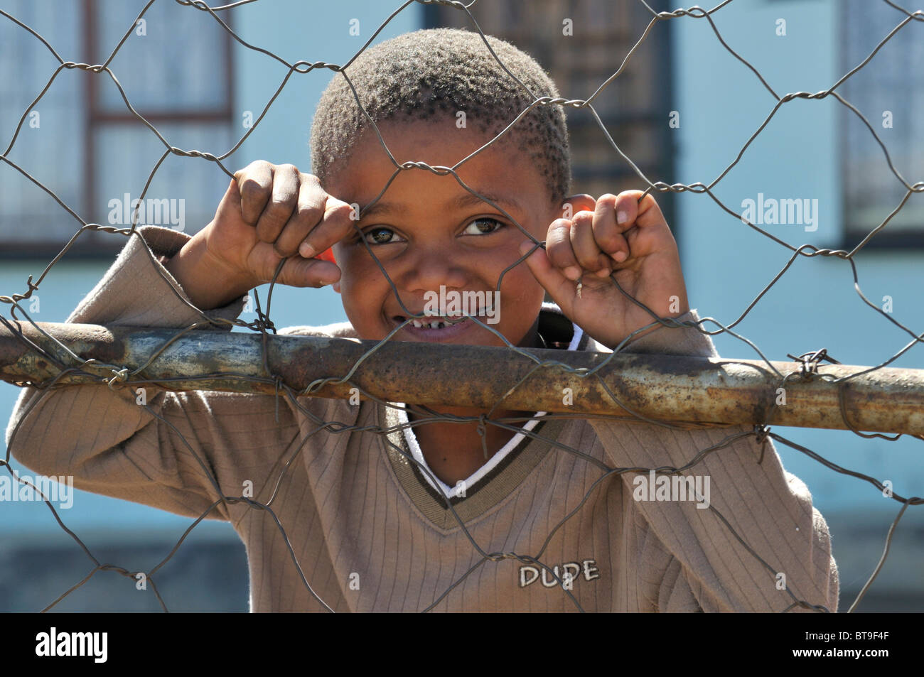 Bildnis eines Knaben hinter einem Maschendraht Zaun, Slum, Township, Queenstown, Eastern Cape, Südafrika, Afrika Stockfoto