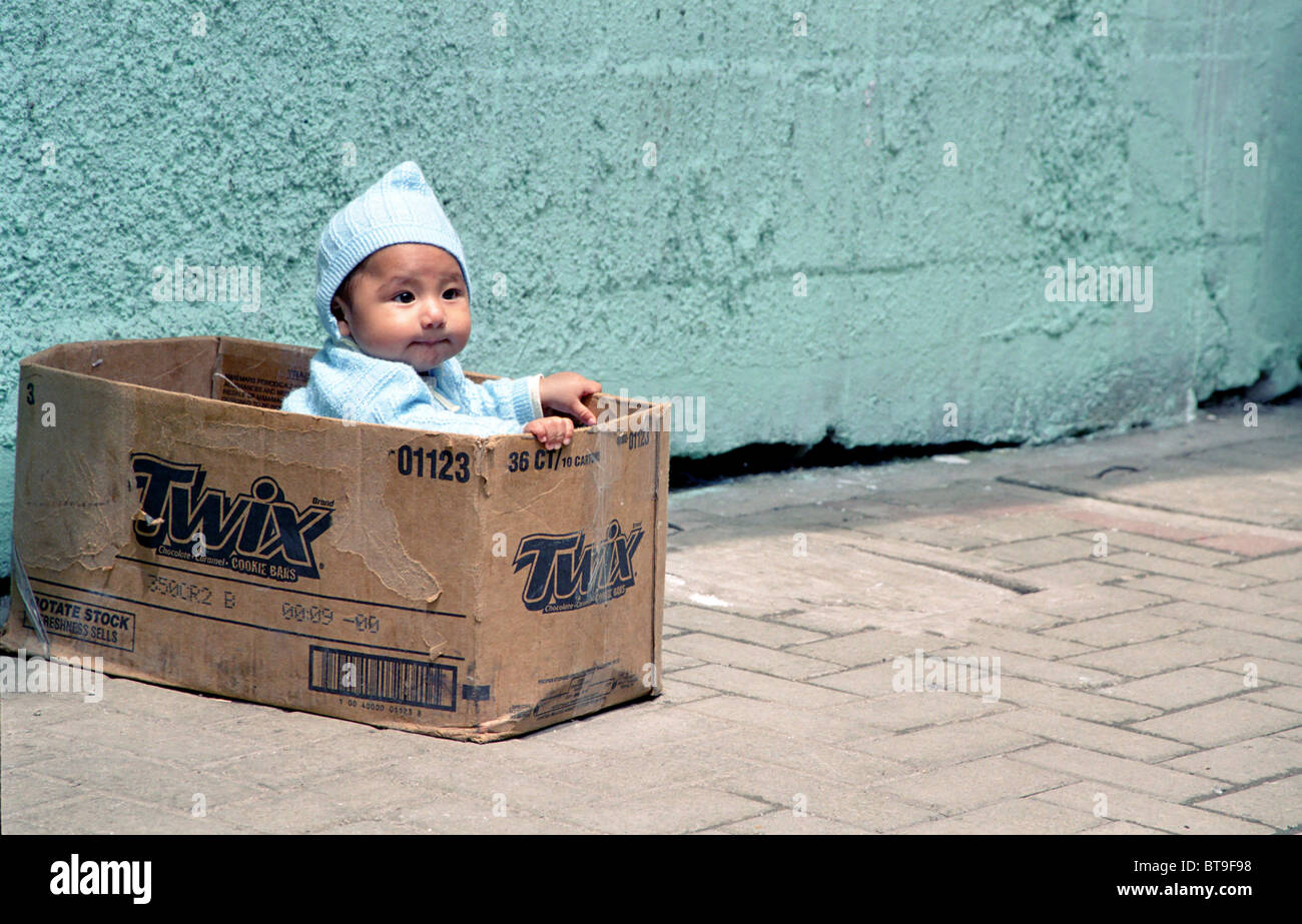 Kleinkind in Twix-Box wartet auf ihre Mutter in Aguas Calientes, Peru, Südamerika Stockfoto
