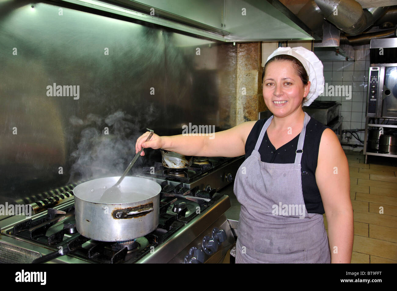 Junge Frau kocht in Tavernenküche, Argostoli, Kefalonia (Cephalonia), Ionische Inseln, Griechenland Stockfoto