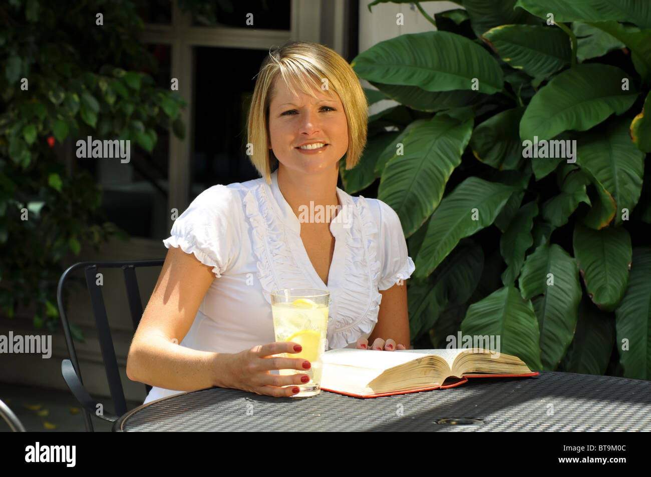 Blonde Studentin Studium mit Lehrbuch und ein Glas Limonade. Stockfoto