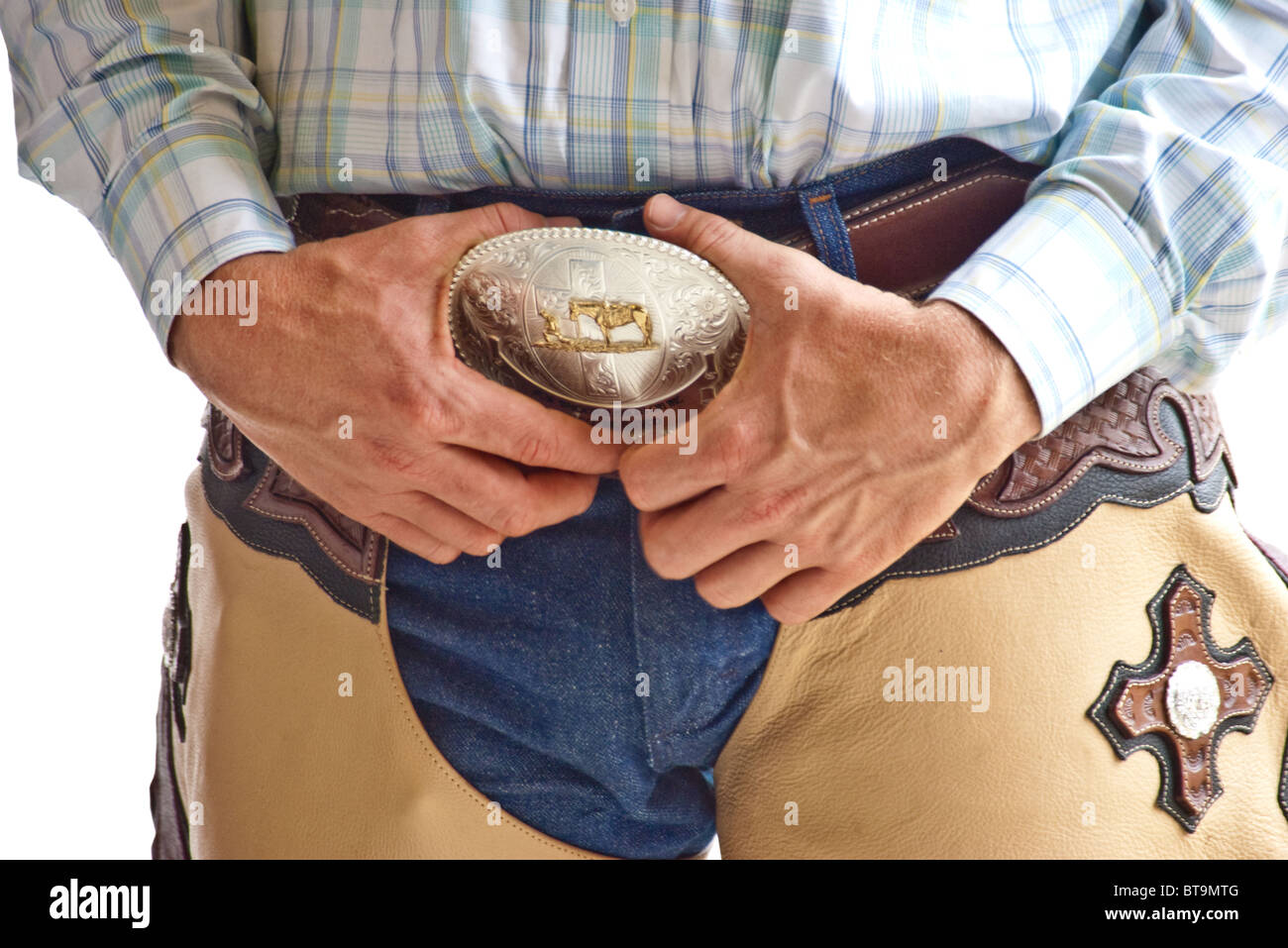 Nahaufnahme eines Cowboys in Chaps ruht seine Hand auf seine große Gürtelschnalle, isoliert auf weißem Hintergrund Stockfoto