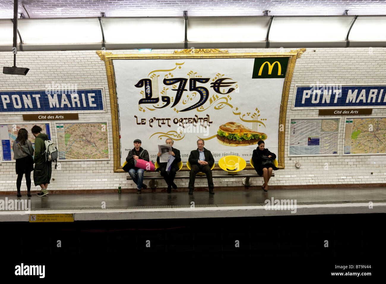 sechs gelangweilt Reisende sind ahnungslos von McDonalds-Werbung für orientalische Hamburger an Wand der Pont Marie u-Bahnstation Paris Stockfoto