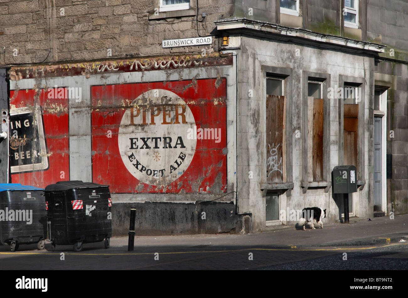 Eine alte Anzeige wird aufgedeckt, nachdem eine Plakatwand an der Ecke von Brunswick Road und Easter Road in Edinburgh, Scotland, UK blies Stockfoto