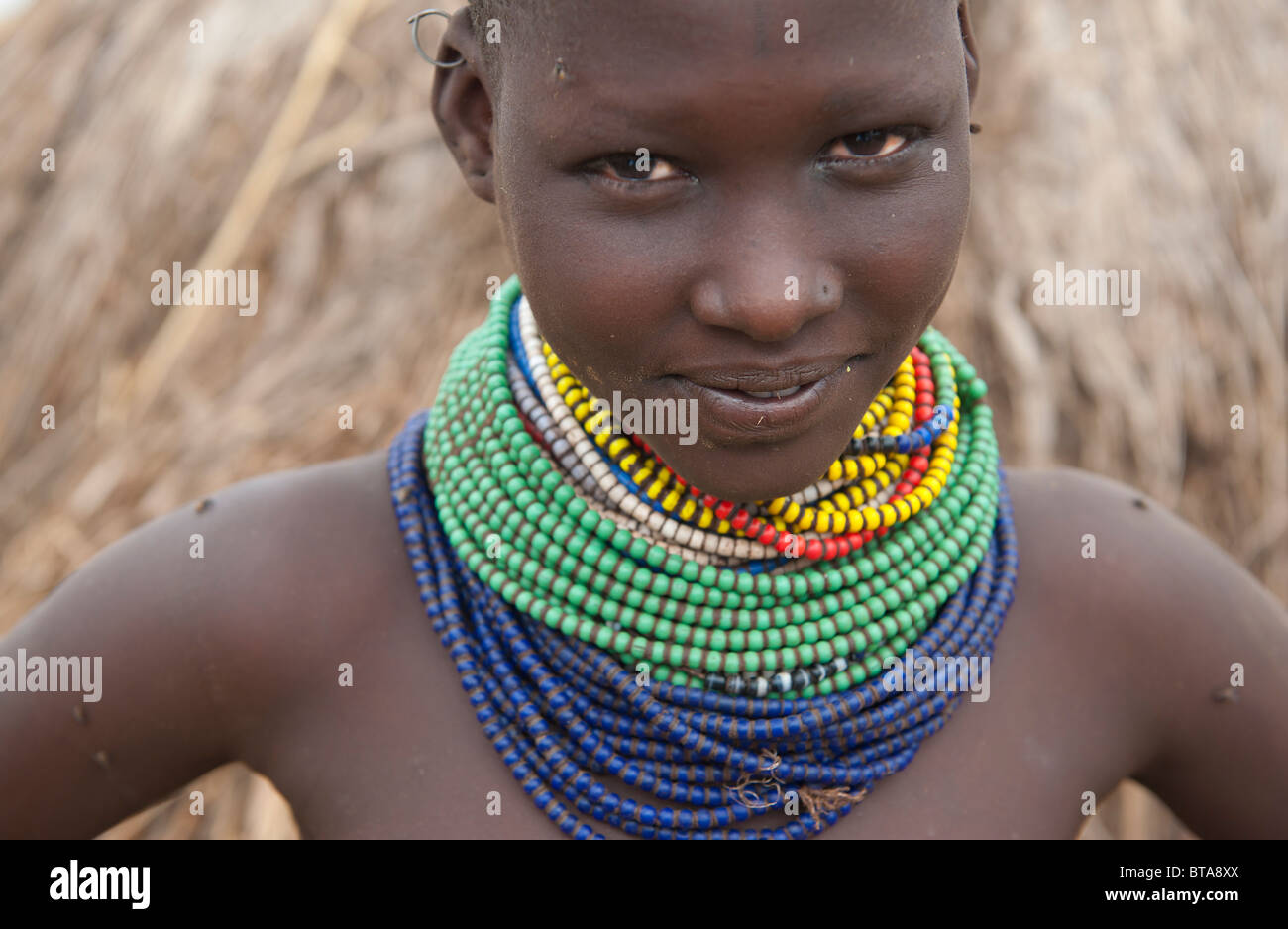 Nyangatom (Bumi) Mädchen mit Haufen von Perlen vor ihrer Hütte, Omo River Valley, Äthiopien Stockfoto