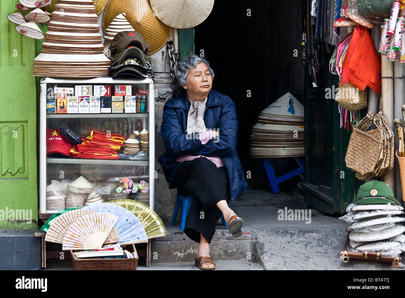 Ein älterer shop Besitzer wartet für Touristen vor ihrer Straßenseite laden in der Altstadt von Hanoi Stockfoto