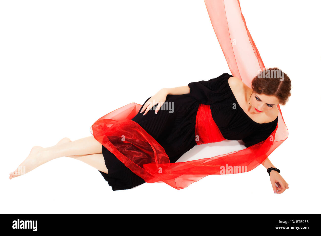 Frau im schwarzen Kleid mit roten Schärpe auf weißem Hintergrund Stockfoto