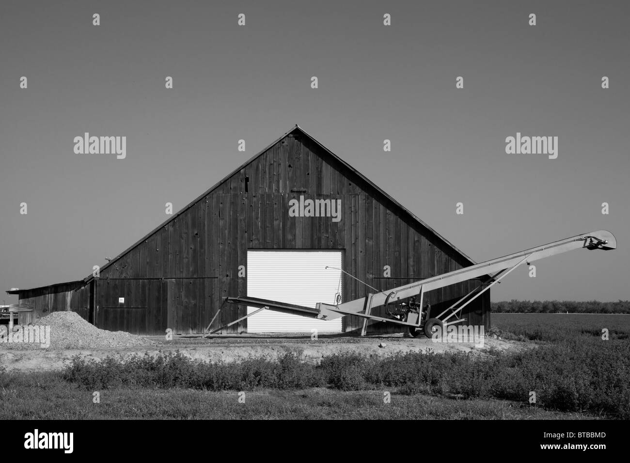Eine alte Scheune mit einer neuen Tür und ein Förderband vor der Tür in Modesto, Kalifornien Stockfoto