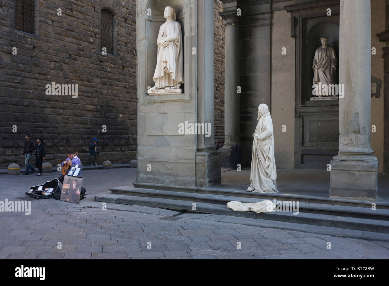Unter den mittelalterlichen Statuen, ein Gitarrist und Straße Straßenmusiker in Florenz Piazza Degli Uffizi. Stockfoto