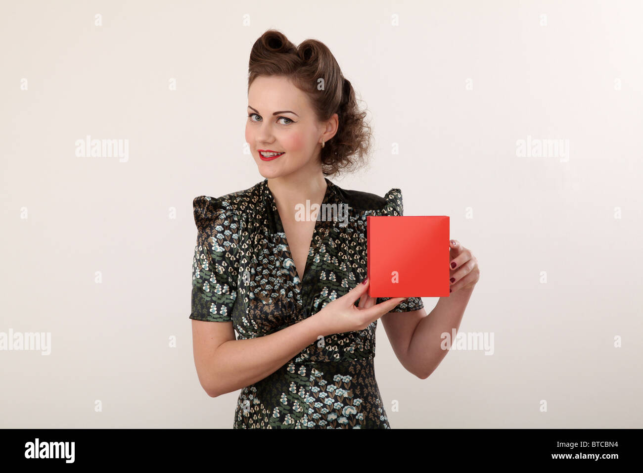 Retro-Hausfrau hält einen roten Karton Stockfoto