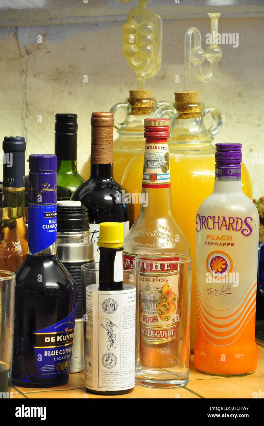 Eine Auswahl an bunten Flaschen voll bereit, um einen cocktail Trank mit Korbflaschen voller Apfel Wind gärenden Liköre Stockfoto