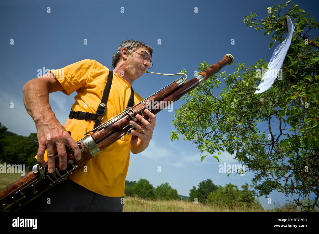 Ein Mann spielt das Fagott im Freien (Auvergne - Frankreich). Joueur de Basson Jouant de Sohn Instrument En Pleine Nature (Frankreich). Stockfoto