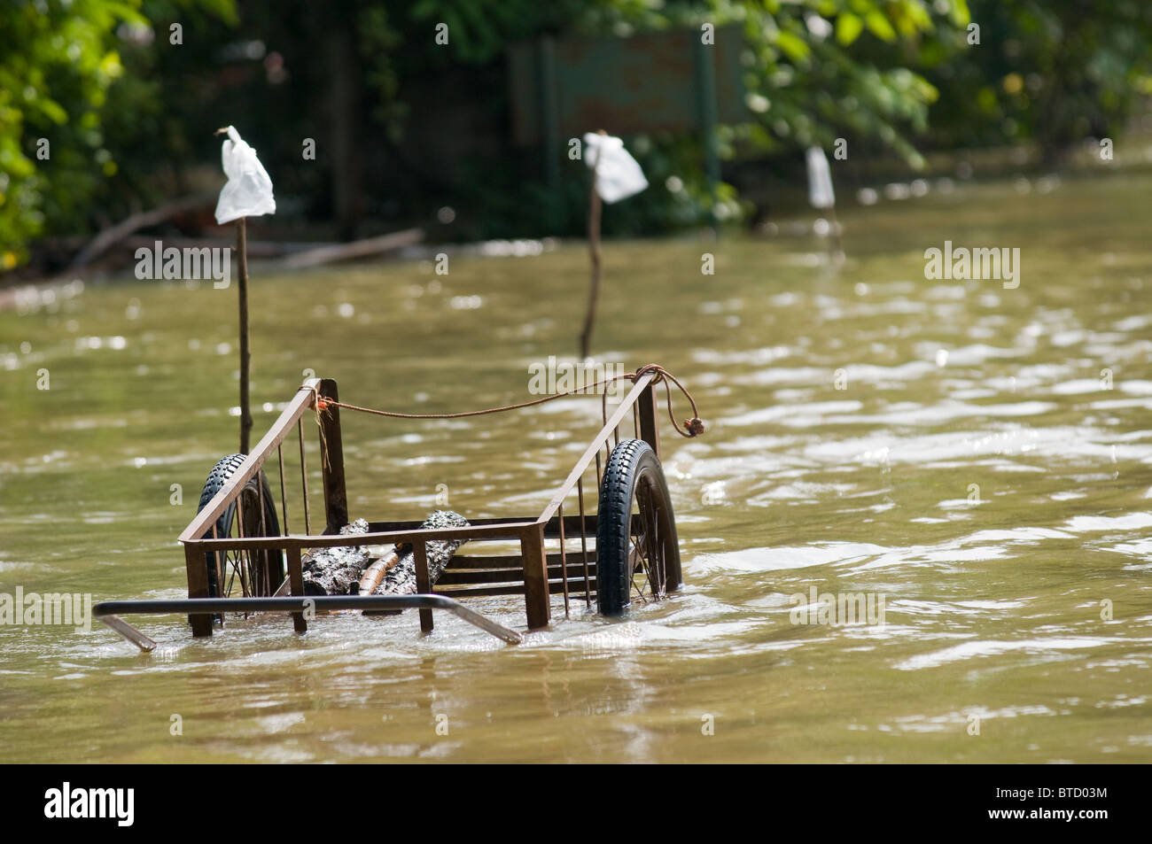 Handwagen verließ im eine überflutete Straße im ländlichen Thailand während der Monsunzeit. Stockfoto