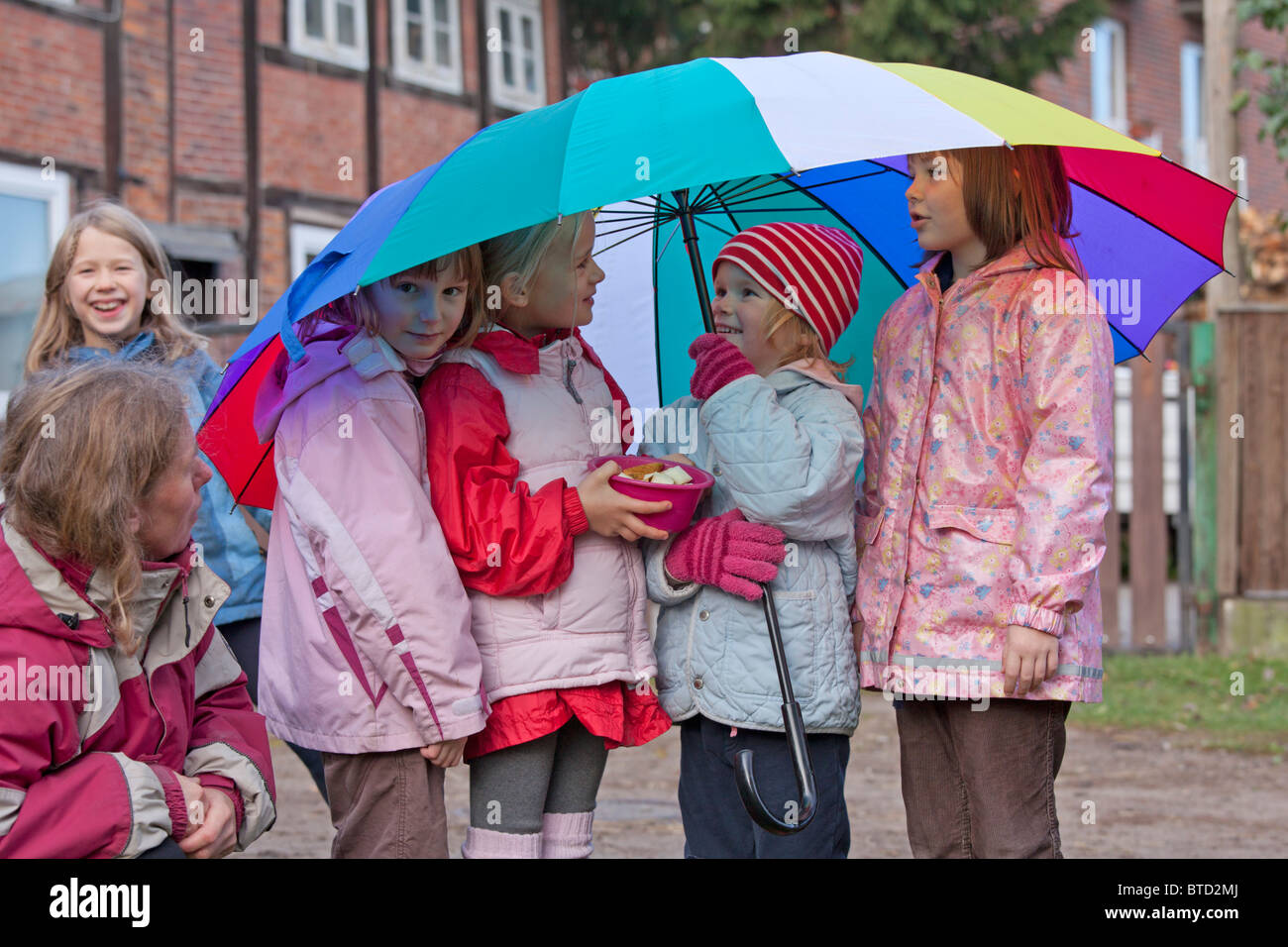 Porträt von vier kleinen Mädchen unter einen bunten Regenschirm Stockfoto