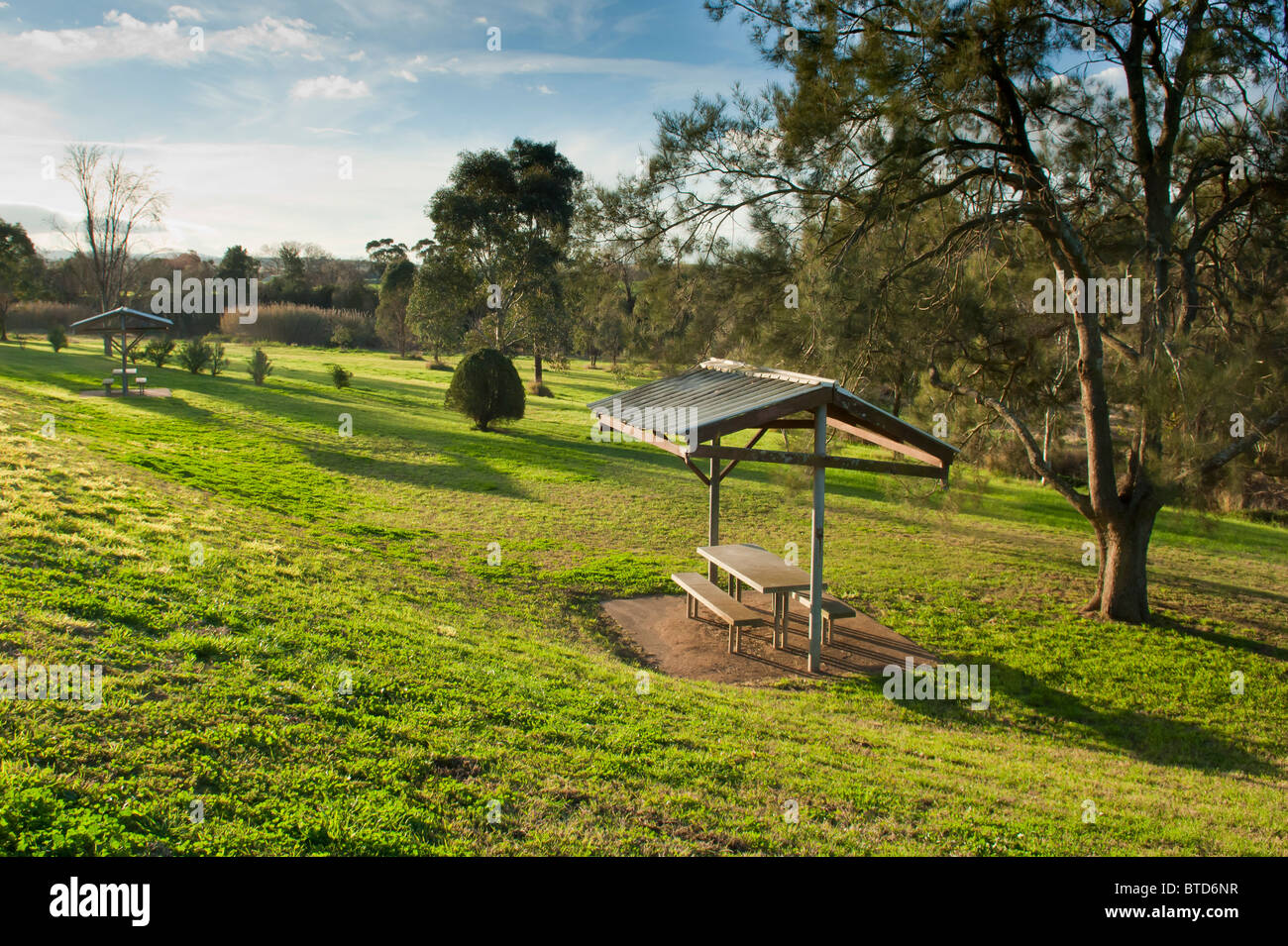 Kleine Schutzhütte in einer grünen Parklandschaft mit Sitzplätzen und einer Tabelle Stockfoto