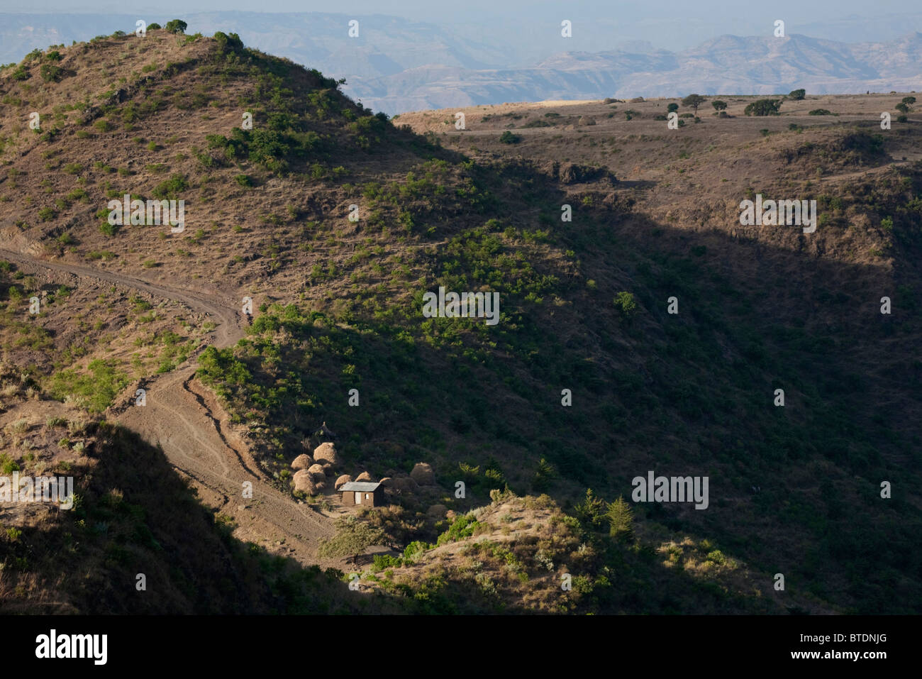 Bergiges Gelände in der Nähe von Lalibela mit einem kleinen Gehöft auf einem Felsvorsprung mit Stapel der geernteten Teff Korn Stockfoto