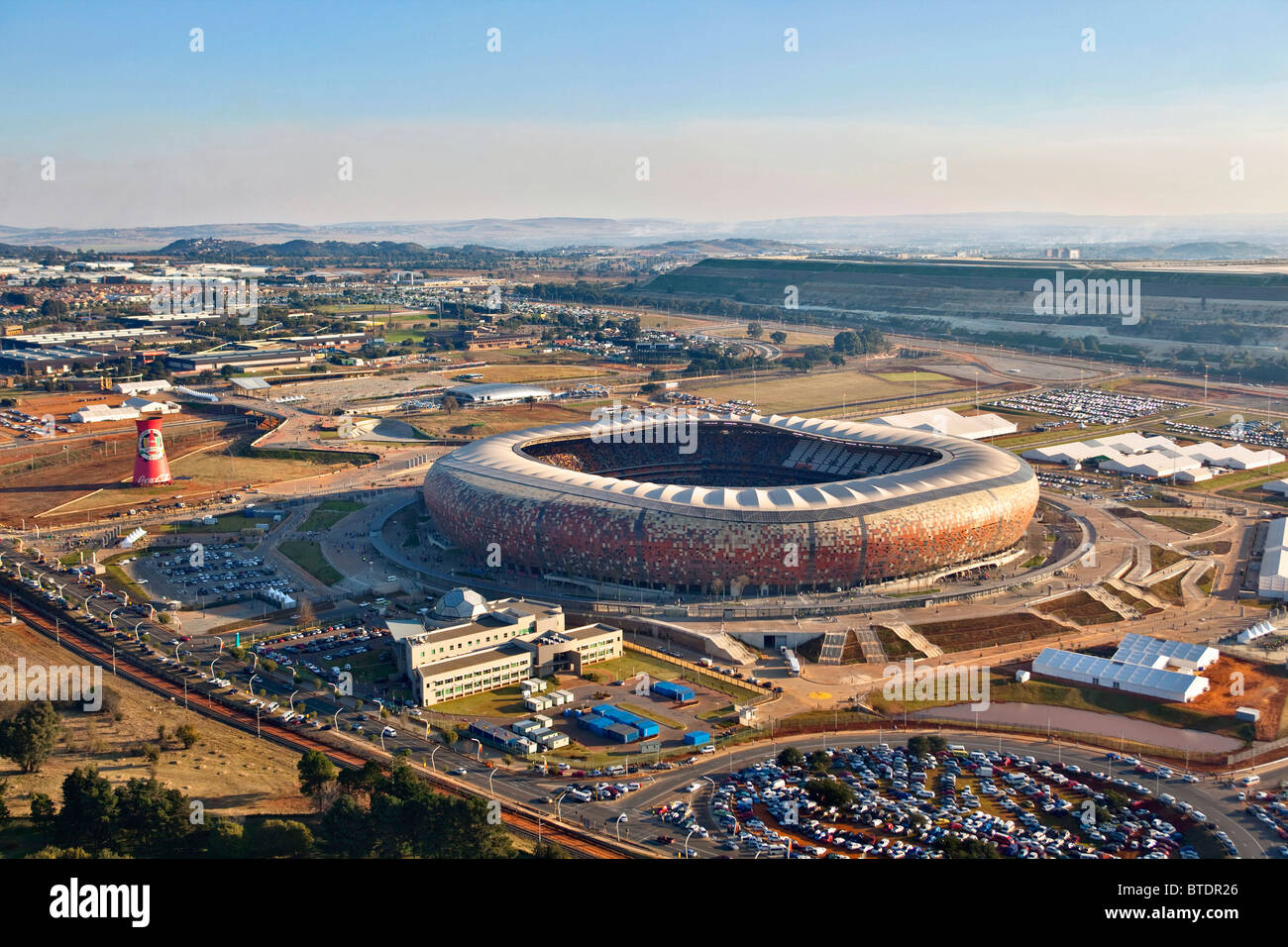 Soccer City Stadion und seine Umgebung mit dem Township Soweto im Hintergrund hinter der Mine-Dump. Stockfoto