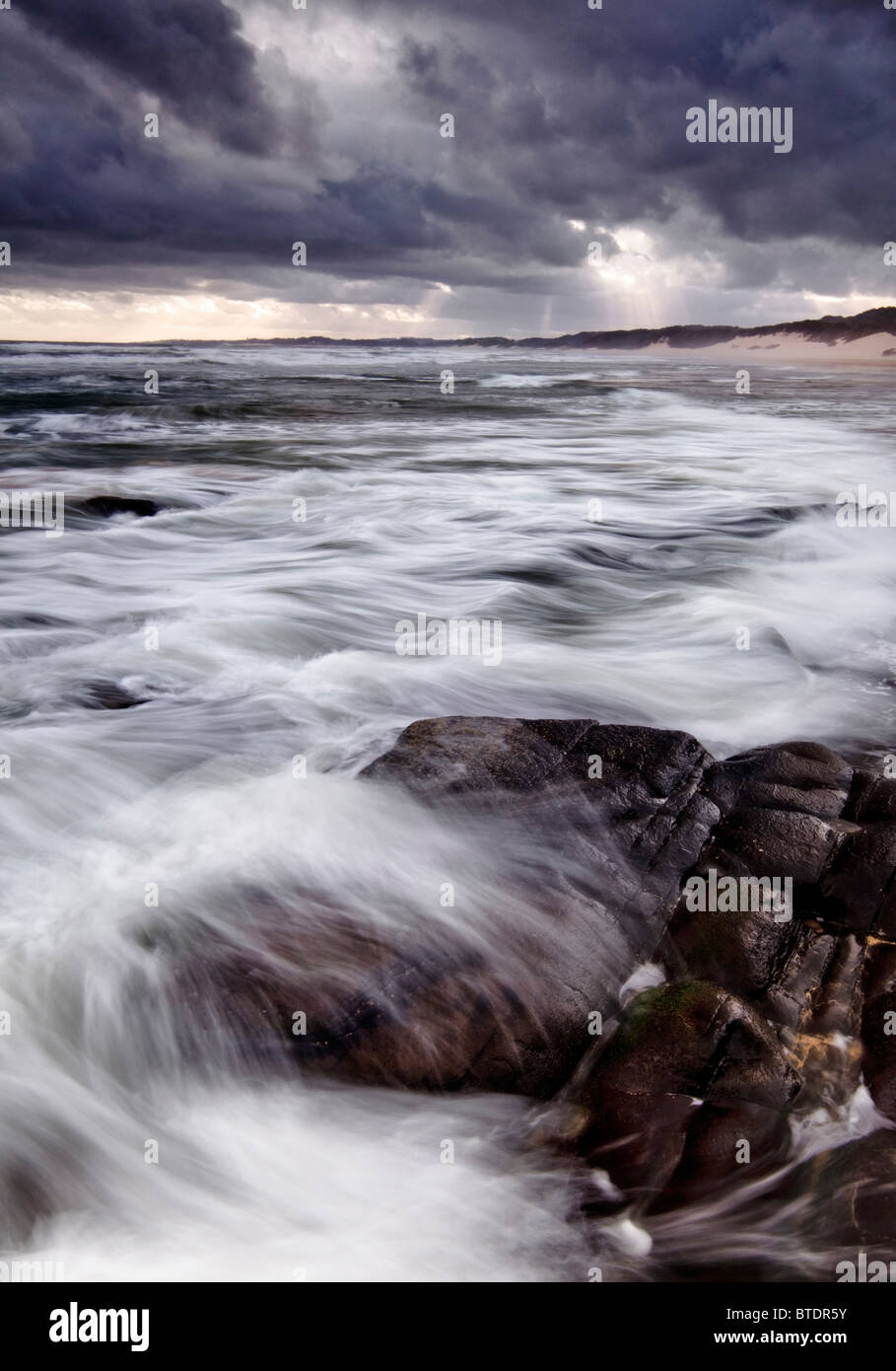 Stimmungsvolle Seestück mit Steinen in den Vordergrund und Beleuchtung über dem Meer Stockfoto