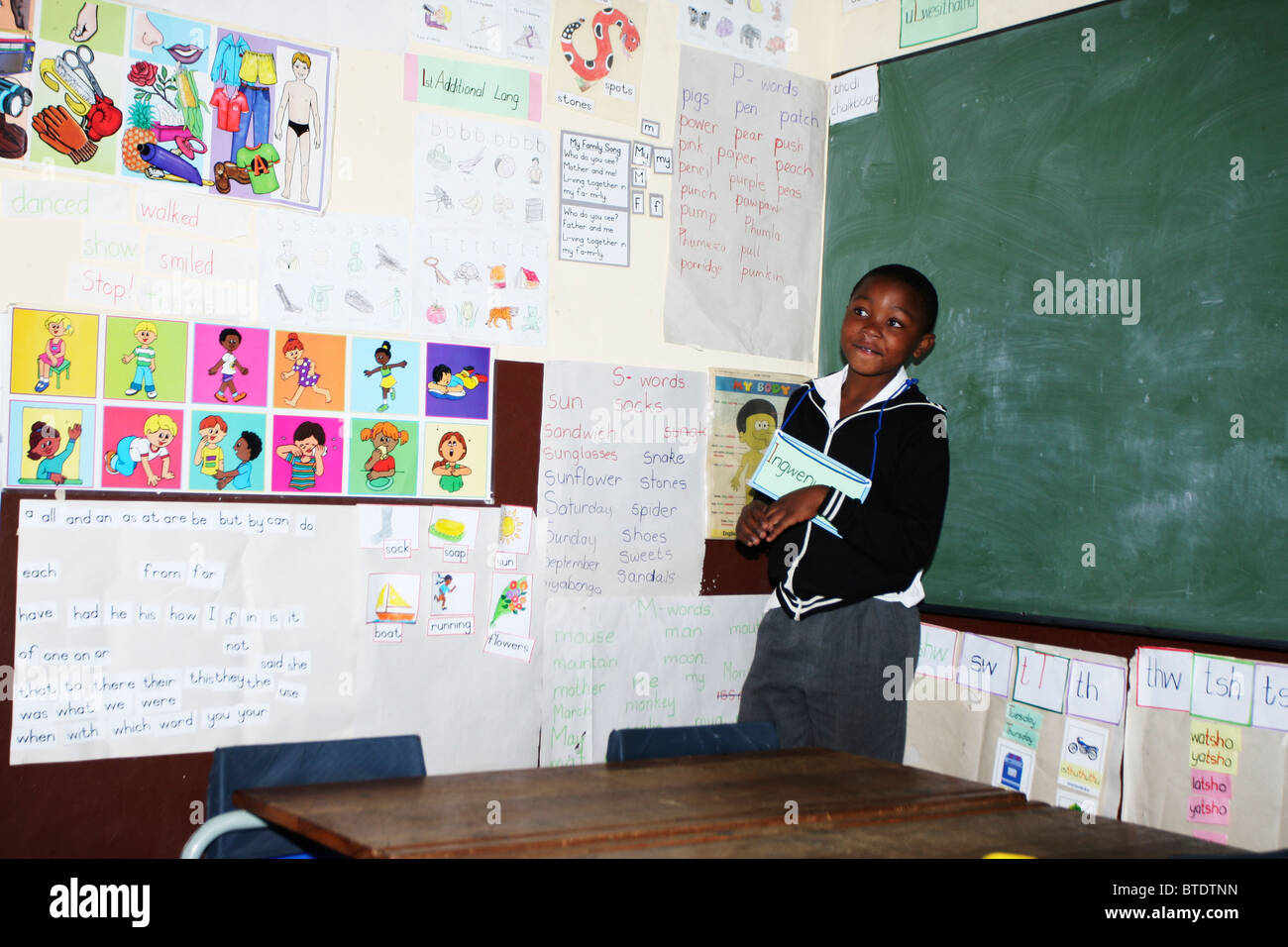 Kleiner Junge stehend in einem Klassenzimmer auf einer Kundgebung zu lesen in einer Landschule in Kwazulu Natal Stockfoto
