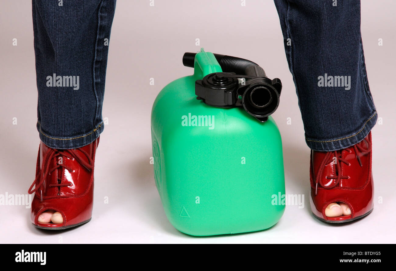 Frau Autofahrer und einer grün gefärbten Kunststoff Benzin können zwischen ihren Beinen Stockfoto