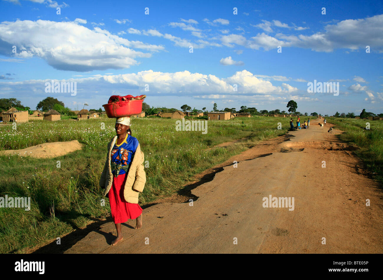 Angolanischen Frau geht auf einer unbefestigten Straße in einem ländlichen Dorf Stockfoto