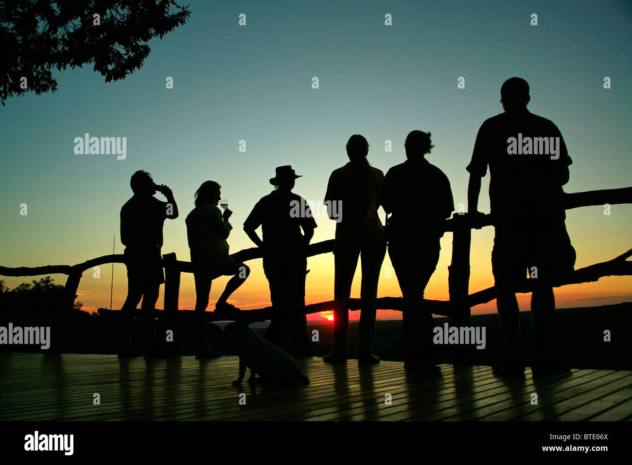 Safari-Touristen mit Sundowner auf dem Deck in Ant es Hill Safari Lodge bei Sonnenuntergang Stockfoto